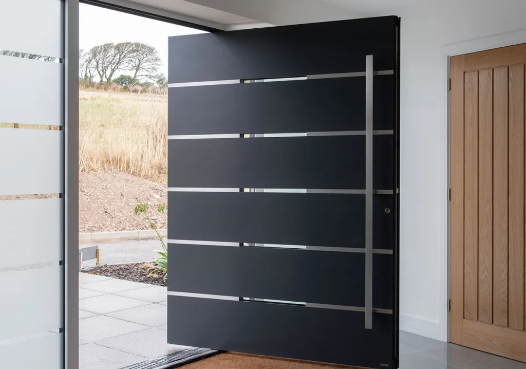 Contemporary wide pivot cast aluminum door featuring horizontal stainless steel inlays and an extra-long vertical door handle.