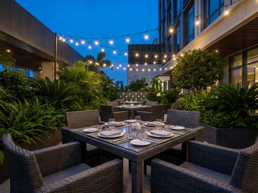 Commercial-grade dark grey rattan furniture used for an elegant outdoor dining set on a high-end hotel restaurant patio at dusk.