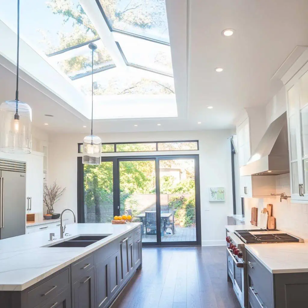 A bright, modern kitchen featuring a large rectangular skylight installed above a custom island, highlighting natural daylight and luxury cabinetry.